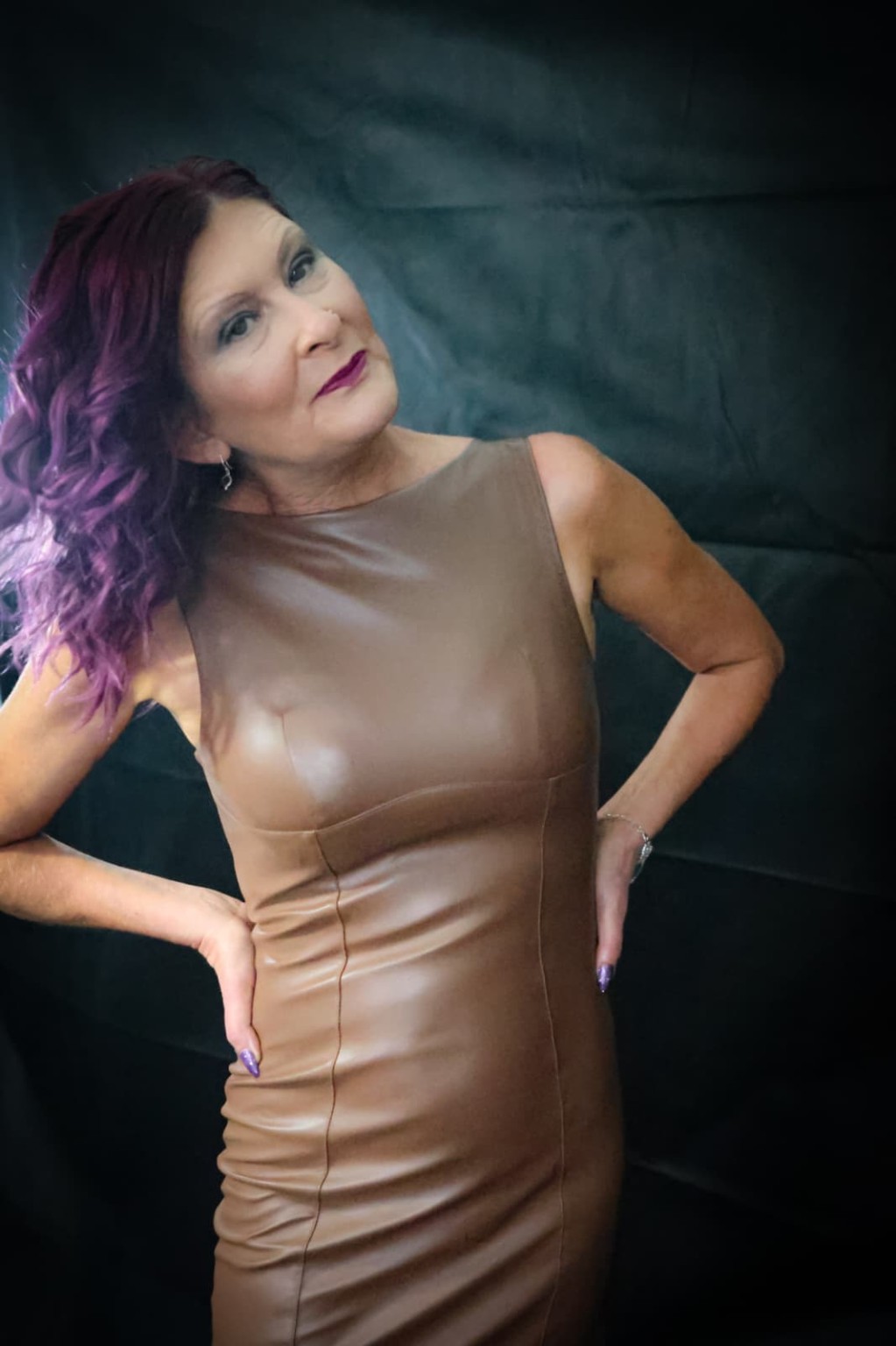 Julie in a brown dress against a dark studio background